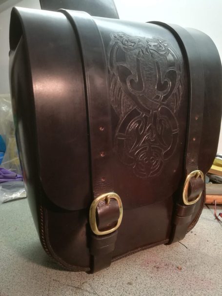 A vintage black leather bag with decorative embossing and brass buckles.
